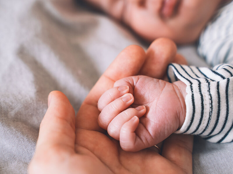 Babyhand liegt in der Hand einer erwachsenen Person.