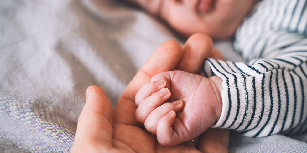 Babyhand liegt in der Hand einer erwachsenen Person.