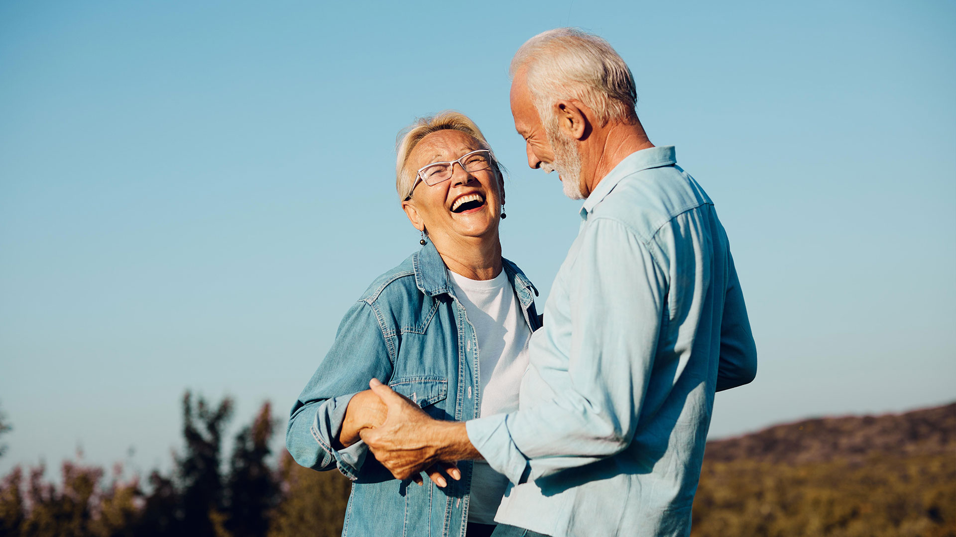 Ältere Frau und älterer Mann lachen glücklich, in der Natur