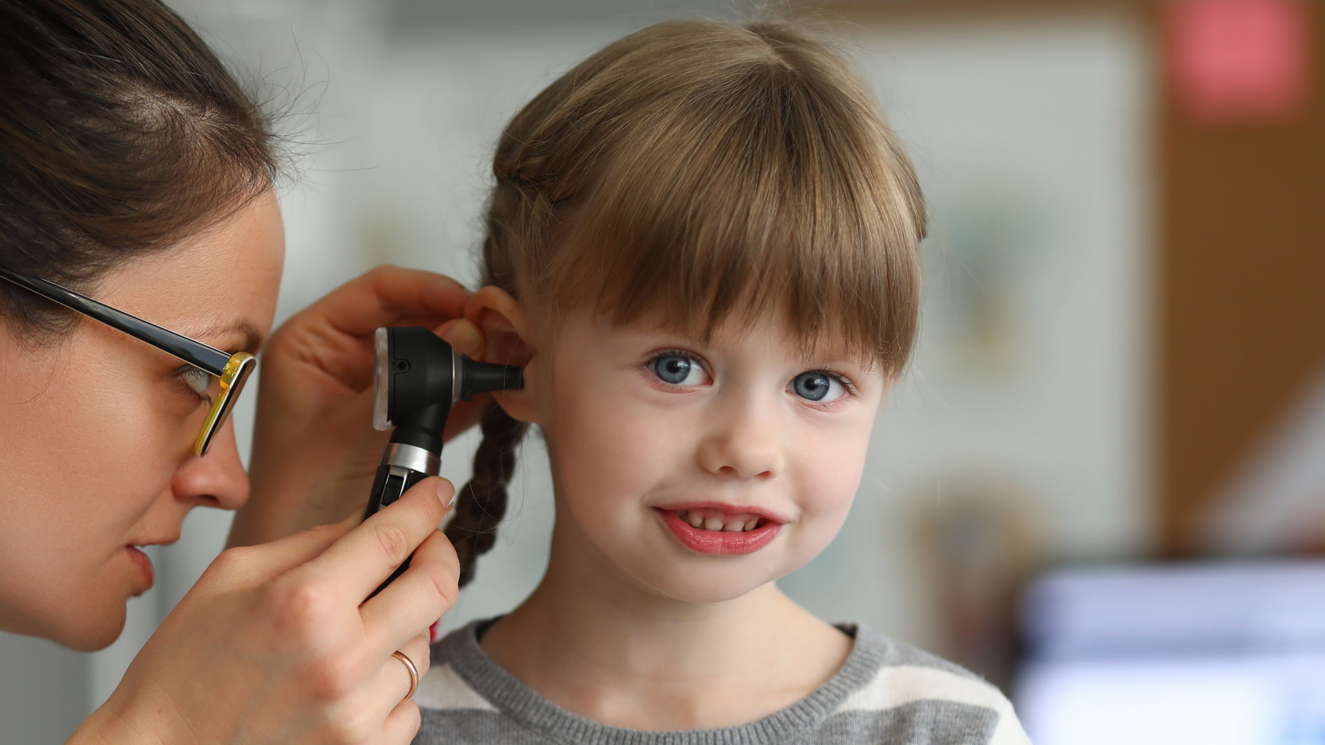 Ein junges Mädchen bekommt von einer Kinderärztin das Ohr untersucht.
