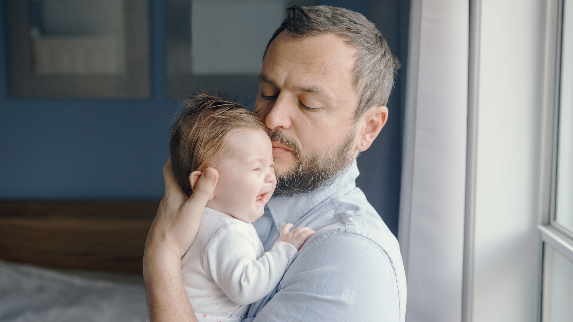 Ein Vater hält ein Baby auf dem Arm und beruhigt es.