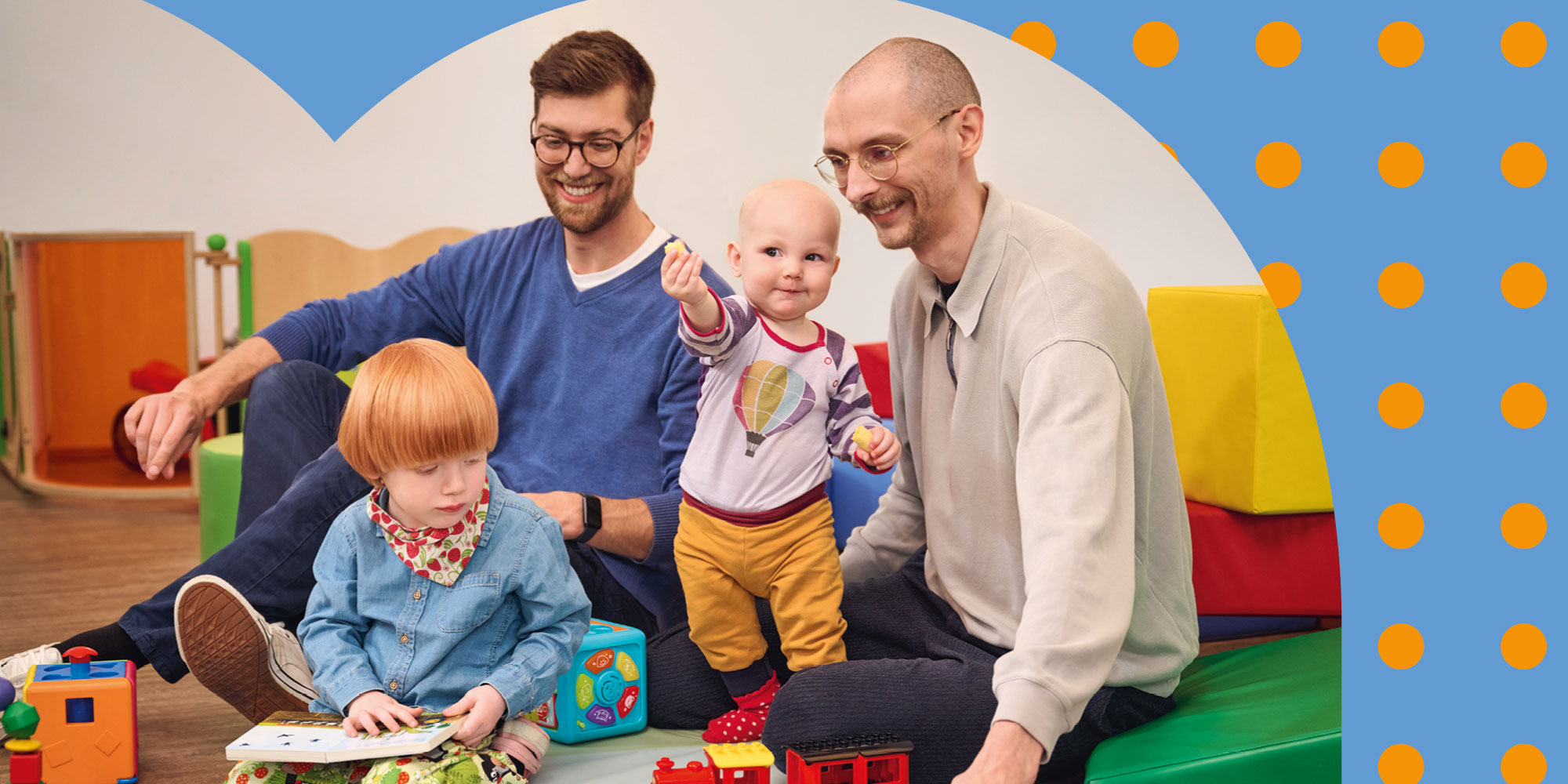 Zwei Väter spielen mit ihren kleinen Kindern auf dem Boden.