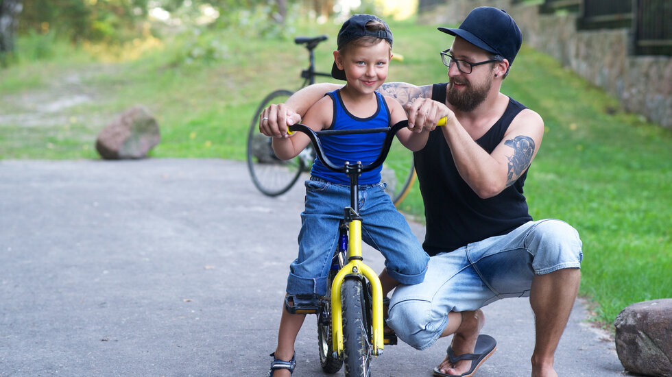 Vater übt mit seinem Kind Fahrradfahren